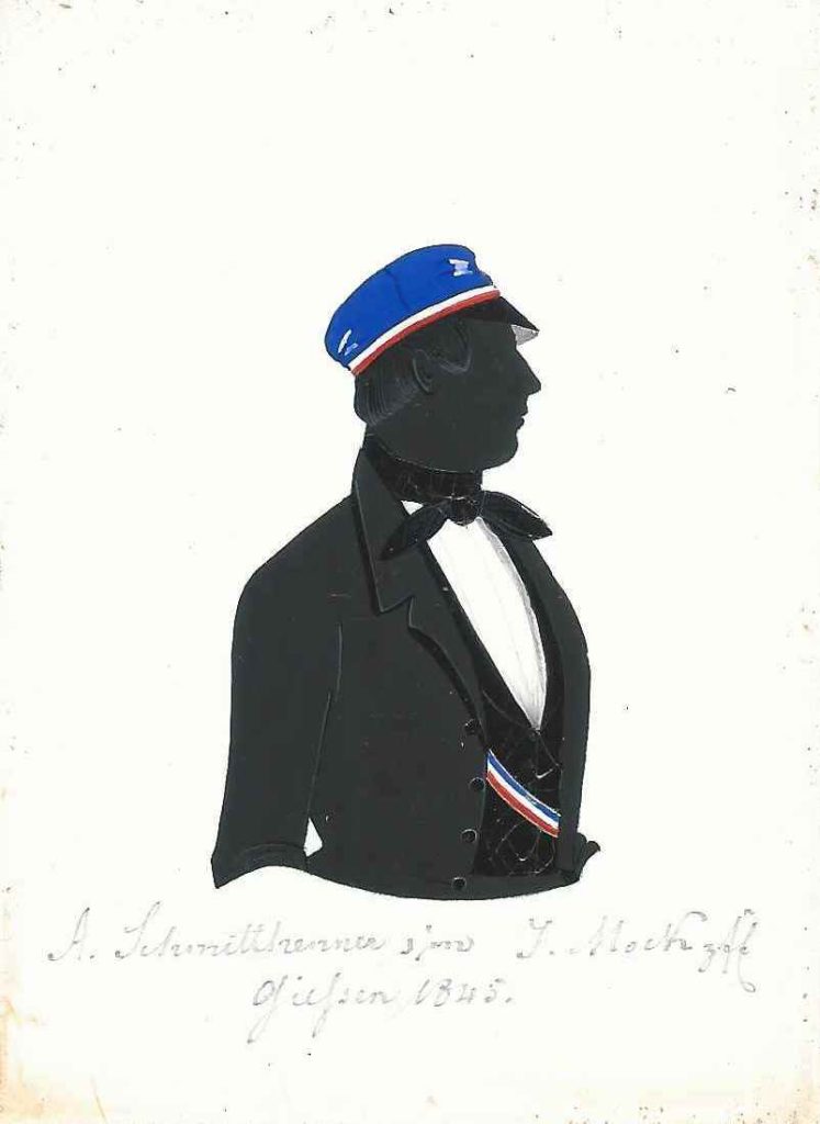 Alexander Schmitthenner stammte aus Gießen. Ostern 1841 immatrikulierte er sich an der Universität seiner Heimatstadt als stud. iur. und trat der Rhenania bei, in die er 1842 rezipiert wurde. Einmal war er Consenior. Er starb als Landgerichtsassessist in Friedberg. Weiteres war bislang nicht über ihn festzustellen. Die Silhouette ist gewidmet "A. Schmitthenner sm J. Mock zfE - Giessen 1845." Kölner Privatsammlung.